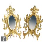 A pair of early 20th Century gilt metal easel back mirrors, each of the bevelled oval mirror