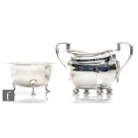 A hallmarked silver boat shaped twin handle sugar basin raised on four ball feet, with a similar