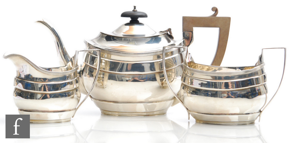 A hallmarked silver boat shaped three piece tea set of plain form each terminating in reeded
