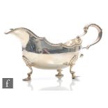 A hallmarked silver sauce boat with waved gadroon border and acanthus capped scroll handle raised on