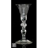 An 18th Century baluster drinking glass circa 1730, the bell bowl above an upper teared knop and