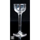 An 18th Century cordial drinking glass, the shallow ovoid bowl above a tall plain stem and shallow