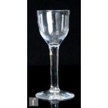 An 18th Century drinking glass, circa 1740, the ogee bowl above a straight plain stem and raised