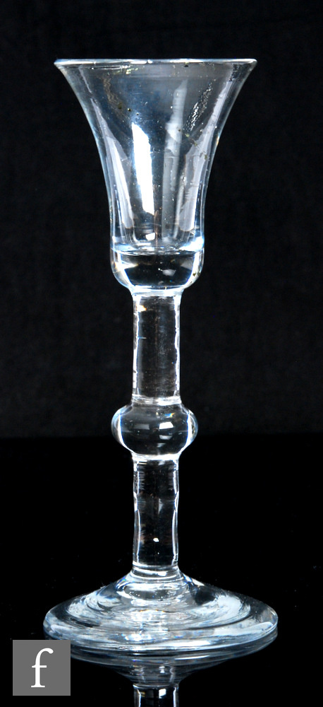 An 18th Century drinking glass, circa 1740, the waisted bell form bowl above a solid stem with large