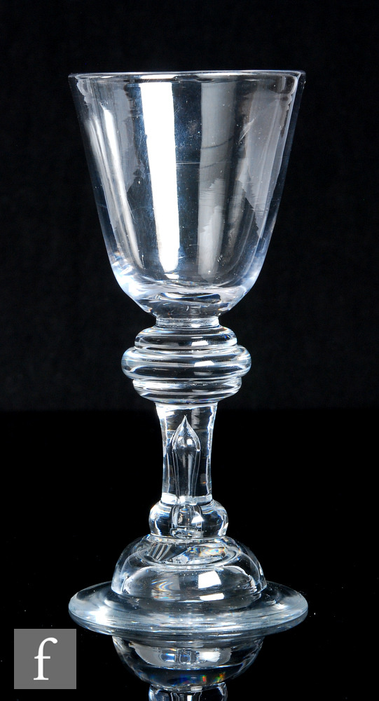 An 18th Century heavy baluster drinking glass circa 1710, the round funnel bowl above a large triple