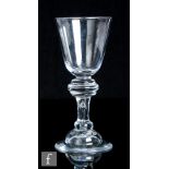 An 18th Century heavy baluster drinking glass circa 1710, the round funnel bowl above a large triple