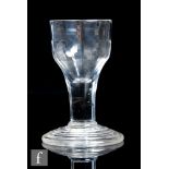 An 18th Century drinking glass, circa 1740, the ogee form bowl with basal fluting above a wide plain