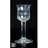 An 18th Century drinking glass, circa 1740, the waisted ovoid bowl over a plain straight stem, the