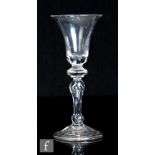An 18th Century drinking glass, circa 1730, the bell bowl with a solid base over a baluster stem
