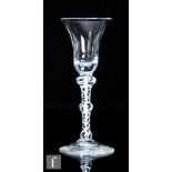 An 18th Century drinking glass, circa 1770, the bell form bowl above a triple knopped opaque twist