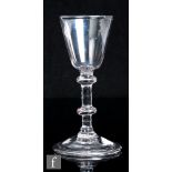 An 18th Century drinking glass, circa 1750, the pointed round funnel bowl above a balustroid stem