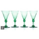 A set of four 19th Century green wine glasses, the conical bowl with basal slice cut decoration