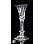 An 18th Century drinking glass, circa 1750, the waisted bell form bowl above an air twist stem