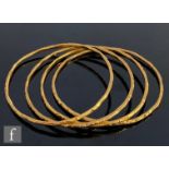 Four 18ct jingle bangles each with bright cut decoration, total weight 48g, unmarked. (4)