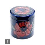 A Moorcroft cylindrical box and cover decorated in the Anemone pattern with tubelined flowers