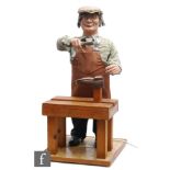 A post 1950s shop automaton display of a cobbler mending a shoe and wearing a flat cap, apron