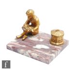 A 1930s desk stand mounted with an inkwell and a figure of a boy seated cross legged holding a model