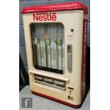 A vintage cast iron Nestle Confectionery wall mounted chocolate vending machine, cream with red