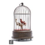A 20th Century Griesbaum singing bird in a cage, the bird with red plumage and perched on a