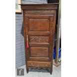 A 19th Century continental hall cupboard enclosed by a triple panel door, the central door carved