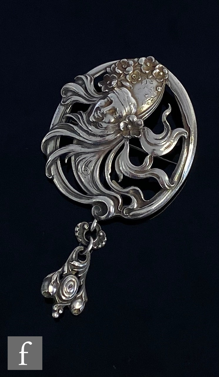 An Art Nouveau American silver brooch designed as the head of a woman with flowing locks above a