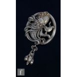 An Art Nouveau American silver brooch designed as the head of a woman with flowing locks above a