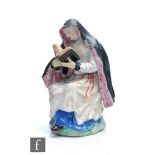A 19th Century Staffordshire model of a seated nun, after Bow in imitation of Meissen, she reading