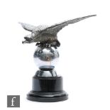 A Desmo chrome car mascot in the form of an eagle perched on a ball, stamped, width 18cm.