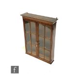 A small 20th Century walnut wall cabinet enclosed by a pair of bar glazed doors below a moulded edge
