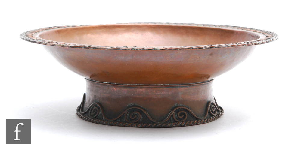A large Arts and Crafts style copper bowl with applied looping border to the rim and scroll to the