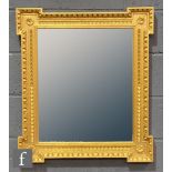 A 19th Century inverted gilt framed wall mirror with florette detail to each corner, bevelled
