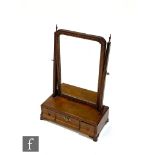 A George III mahogany dressing table mirror, the shaped parcel gilt plate over a base fitted with