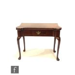 A George III mahogany fold over tea table, the shaped projected top over a small frieze drawer on