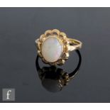 A 9ct hallmarked opal single stone ring, collar set stone within a pierced scalloped border,