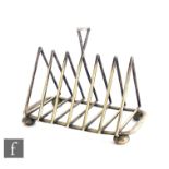 An early 20th Century silver plated six division toast rack of triangular form raised on four bun
