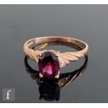 A 9ct hallmarked rose gold rhodalite and diamond three stone ring, central rhodalite flanked by