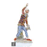 An early 20th Century Meissen Commedia dell'arte figure of a harlequin with one armed raised and the