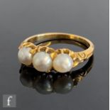 An early 20th Century 18ct split pearl three stone ring, all claw set to scroll detailed