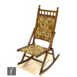 A late Victorian walnut spindle back steamer rocking chair with tapestry fabric seat and back.