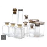 A collection of eleven silver top and silver plated glass cologne and scent bottles from a