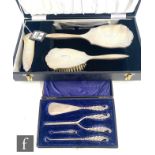 A cased hallmarked silver backed four piece brush set with engine turned decoration, with a cased