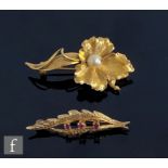 An 18ct brooch modelled as a flower and set with a single pearl, weight 5.8g, with a similar 9ct