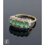 A 9ct hallmarked emerald and diamond ring, five oval claw set emeralds within a border of