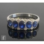 A platinum hallmarked sapphire and diamond ring, five oval collar set sapphires spaced by diamonds