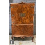 A mid 20th century Queen Anne style walnut cocktail cabinet, the mirrored interior enclosed by a