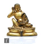 A Sino-Tibetan gilt bronze figure of Shariputra, the Buddhist disciple seated holding a lotus pod