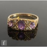 An Edwardian style 9ct hallmarked seven stone amethyst and diamond ring, all to scroll detailed