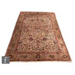 A Heriz style carpet, the central ivory ground set within green and rich salmon pink borders,