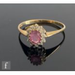 A 9ct hallmarked pink sapphire and diamond cluster ring, central sapphire within a diamond set
