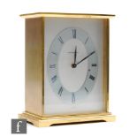 A 1970s lacquered brass clock by Garrard, silvered dial and oval chapter ring, presentation